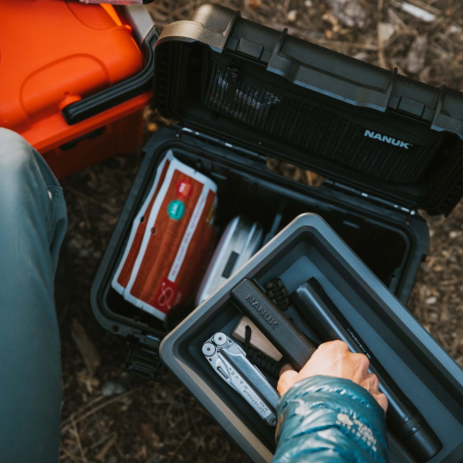 Top-down view of a NANUK Trail 10 case inside a car trunk, with hands arranging camera equipment in its foam inserts.