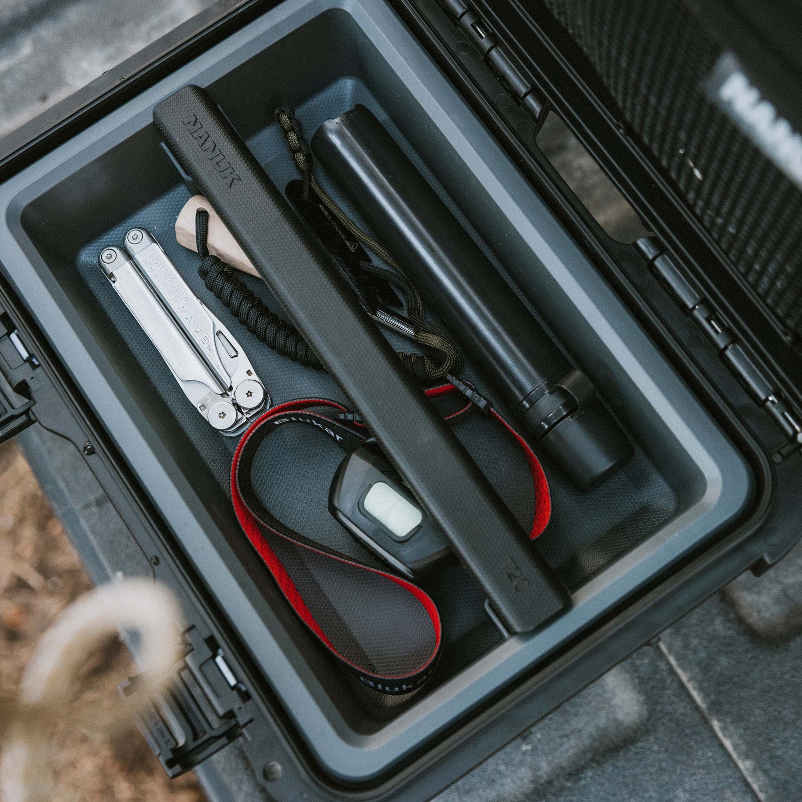 Interior shot of a NANUK Trail 10 case open on a vehicle floor, showing neatly organized tools, cables, and camera accessories.